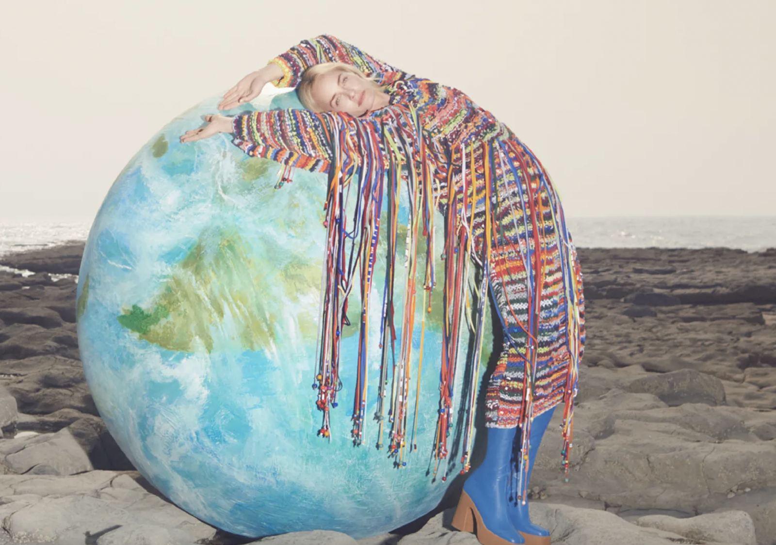 A model leaning on a globe in a Stella McCartney ad