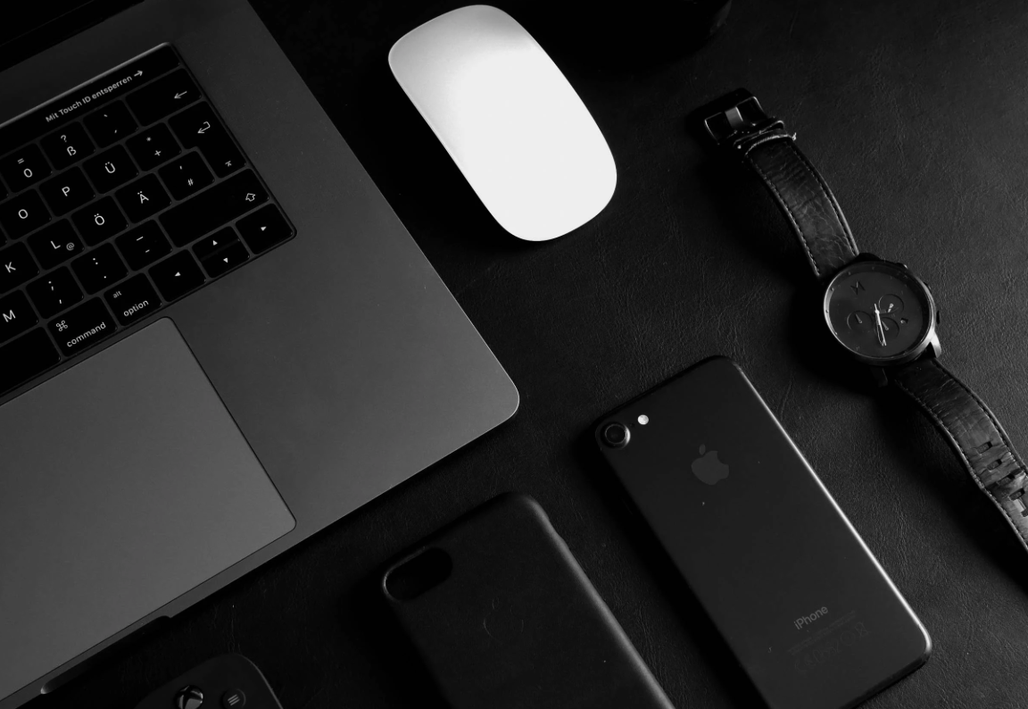 A computer, mouse, and watch on a desk